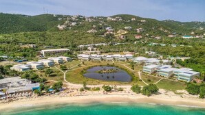 An aerial view of a coastal resort with multiple buildings, a beach, and a small lake. - Lovely Sapphire Beachfront Condo - Snorkel Crystal Cove - Paradise ! (St Thomas)