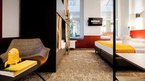Une chambre d’hôtel avec un lit, un bureau et une chaise, une fenêtre et un panneau accroché au mur.