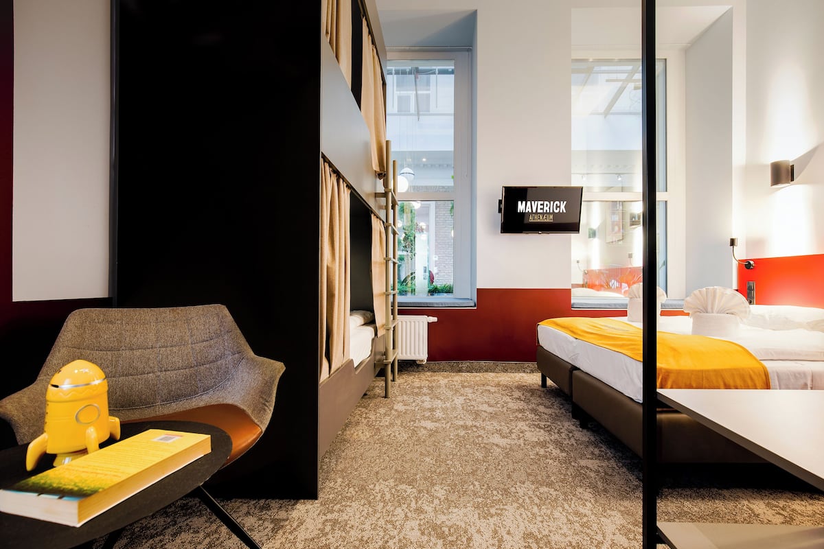 Een hotelkamer met een bed, een bureau met stoel, een raam en een bord aan de muur.