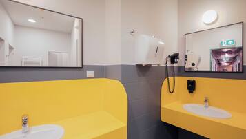 Un baño moderno con dos lavabos, un espejo y un secador de manos.