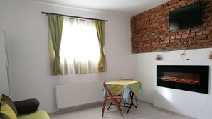 A living room with a brick wall, a fireplace, a table with a tablecloth, and a sofa. - Courage place is sunny (Cluj-Napoca)