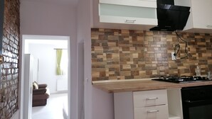A kitchen with a tiled backsplash, a stove, and white cabinets. - Courage place is sunny (Cluj-Napoca)