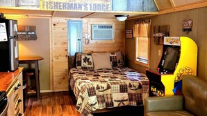 A cozy cabin interior with a bed, a couch, a dining area, and a small kitchen.