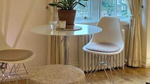 Une pièce avec une table ronde, deux chaises, une plante en pot et un radiateur.