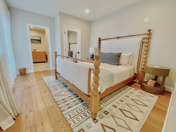 Un dormitorio con cama con dosel, una mesita de noche con lámpara y una alfombra de diseño geométrico.