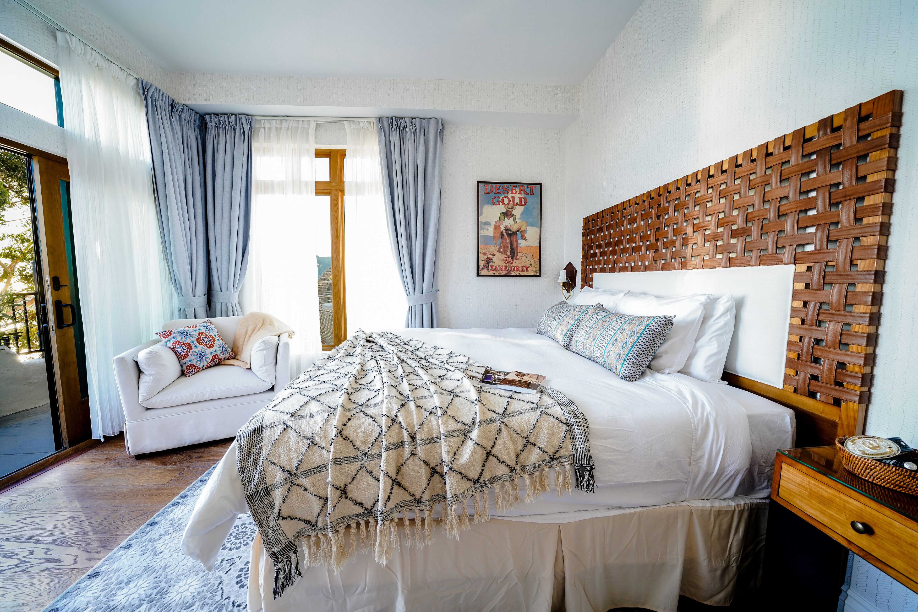 A bedroom with a large bed, a sofa, a wooden headboard, and a poster on the wall.