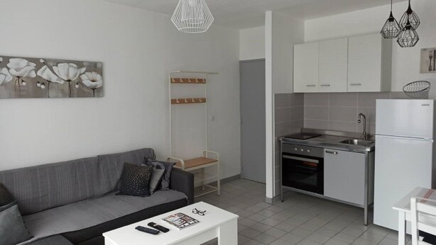 Una cocina moderna con armarios blancos, una estufa de acero inoxidable y un refrigerador blanco.