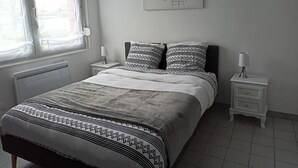 Un dormitorio con una cama, dos mesitas de noche, una ventana y una obra de arte colgada en la pared.