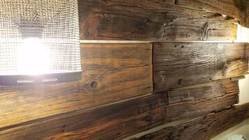 A rustic wooden wall with a textured light fixture and a bed with a quilted blanket.