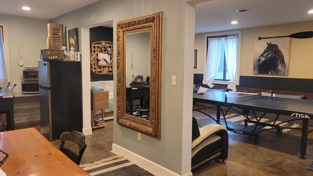 A dining area with a table and chairs, a large mirror, and a painting of a horse on the wall.