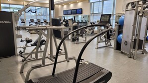 Een fitnessruimte met loopbanden, krachttrainingsapparaten en fitnessballen.