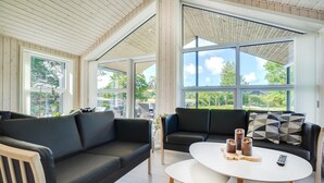 A spacious living area with two black sofas, a white coffee table, and large windows offering a view of greenery. - Amazing home in Rømø with WiFi (Rømø)