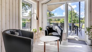 A modern interior with a sofa, a small table, and a chair. There are large windows and a view of the outdoors. - Amazing home in Rømø with WiFi (Rømø)