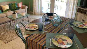 A dining area with a table set for four, surrounded by a green sofa and a coffee table with a plant.