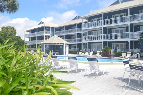 A multi-story hotel with a pool area, including lounge chairs and a small gazebo.