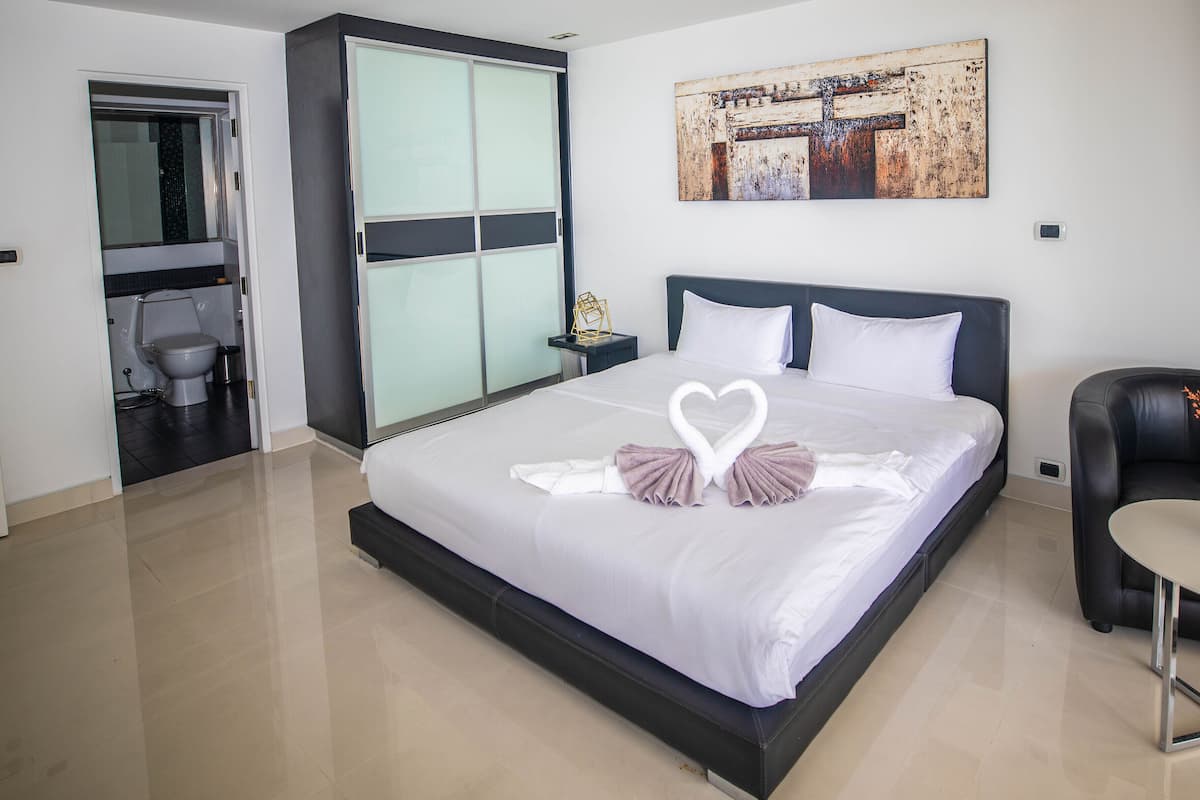 A modern hotel room with a large bed, a separate bathroom, and a small table with a vase.