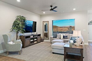A living room with a TV, a large plant, a sofa, a coffee table, and a fireplace.