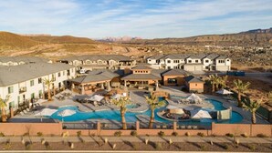 Resort com vários edifícios, área de piscina central e montanhas ao fundo.