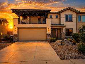 A two-story house with a garage, a balcony, and a stone foundation.