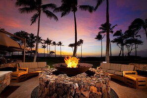 A stone fire pit surrounded by wooden furniture, set against a backdrop of palm trees and a sunset sky. - WESTIN KAANAPALI 5 STAR OCEAN RESORT
5 + Miles from Lahaina (Maui)