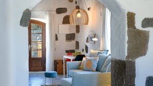 A cozy living area with a stone wall, a blue sofa, and a hanging light fixture. - Luciana, La Casa del Medianero (Macher)