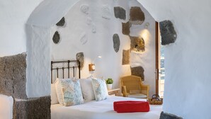 A cozy bedroom with a stone wall, a bed with pillows, a chair, and a nightstand with a lamp. - Luciana, La Casa del Medianero (Macher)