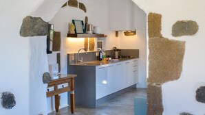 A kitchen with a central island, white cabinets, a microwave, and a stone archway. - Luciana, La Casa del Medianero (Macher)