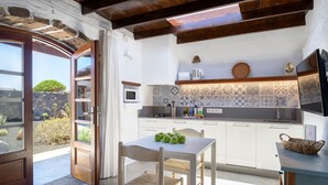 Una cocina moderna con armarios blancos, salpicadero de azulejos y un comedor con mesa y sillas.