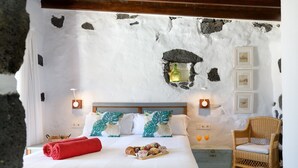 Una cama con edredón blanco, una toalla roja y una bandeja de pasteles.