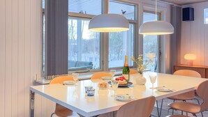 Un espace repas avec une table blanche, plusieurs chaises et des luminaires suspendus.