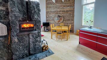 Ein modernes Wohnzimmer mit Kamin aus Stein, einem Holzespeisetisch und roten Schränken.