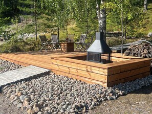A wooden deck with a built-in fireplace and seating area.