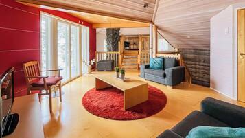 Un salon moderne avec un plafond en bois, un mur d’accent rouge et une grande fenêtre.