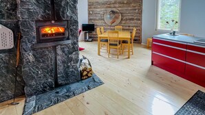 Een moderne leefruimte met een stenen open haard, een houten eettafel en rode kasten.