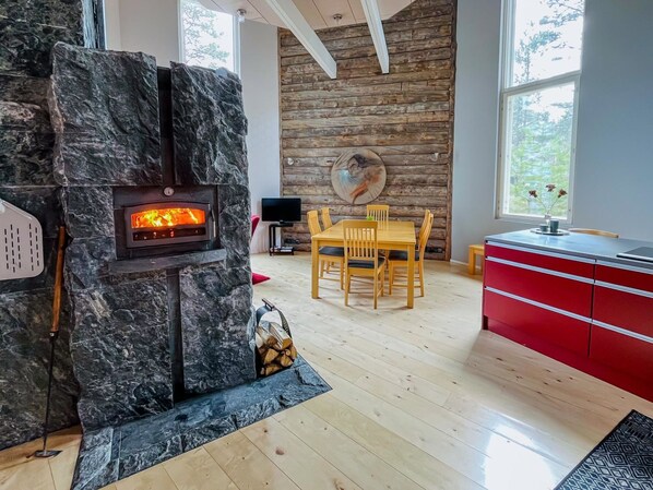 Un espace de vie moderne avec une cheminée en pierre, une table à manger en bois et des meubles de rangement rouges.