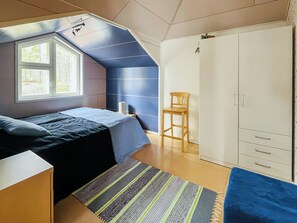 Un dormitorio con una cama, una silla, un armario y una ventana.