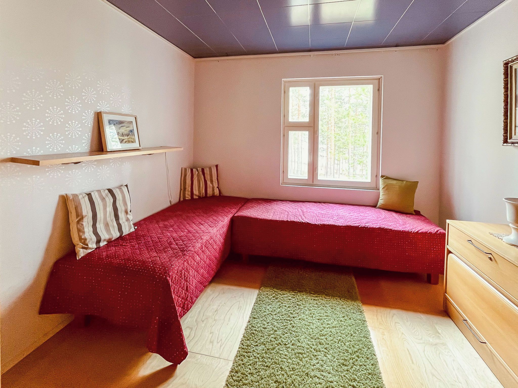 Ein Schlafzimmer mit einem Bett, einem Fenster, einer Kommode und einem Regal mit einem Bild.