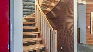 Eine Holztreppe mit Handlauf, die zu einem Raum mit strukturierter Wand führt.