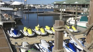 A marina with several jet skis docked at wooden piers.