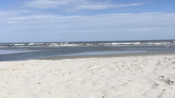 A beach with a wide sandy shore and the ocean in the background.