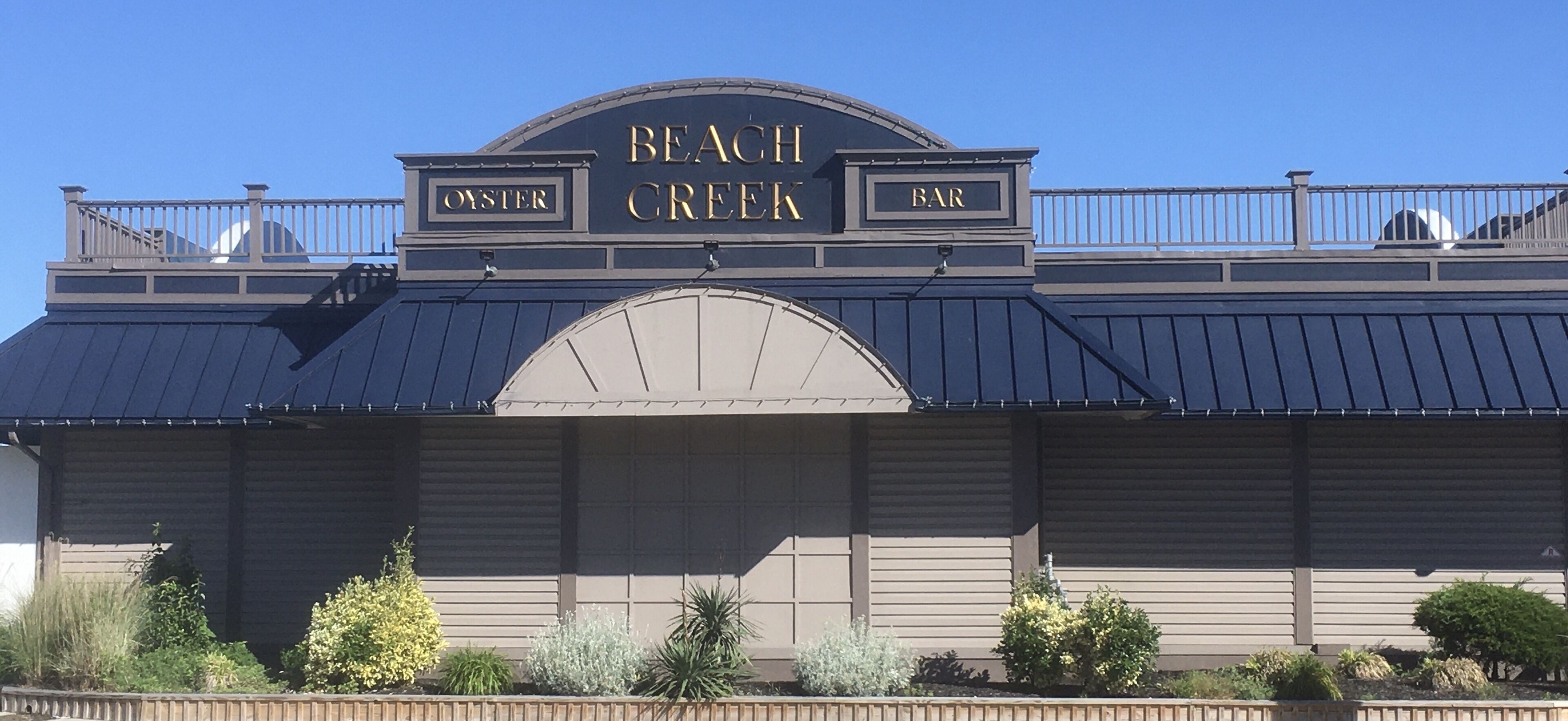 Un edifici amb un rètol que diu 'Beach Creek Bar' i 'Oyster' a la part superior.