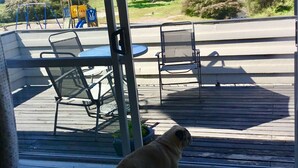 Un terrazzo con mobili da esterno, un cane e vista sul mare.