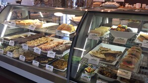 Una vetrina di pasticceria con diversi prodotti da forno e insalate.