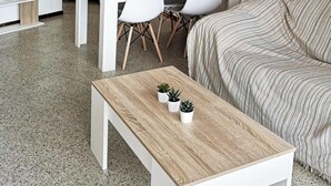 Una sala de estar moderna con una mesa de centro de madera, un sofá a rayas y un comedor con una mesa de madera y sillas blancas.
