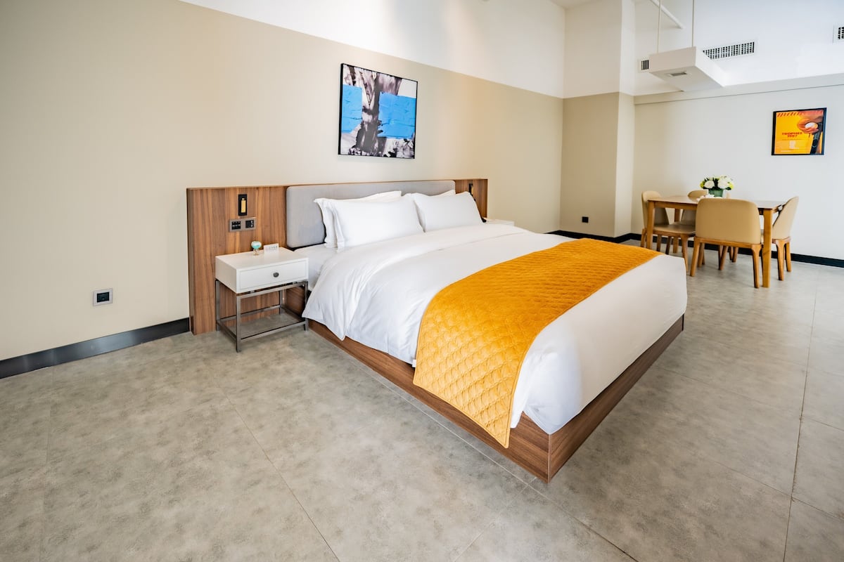 A hotel room with a large bed, a desk, and a chair.