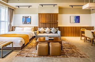 Una camera d'albergo moderna con un letto, un divano, un tavolino da caffè e un'area pranzo.