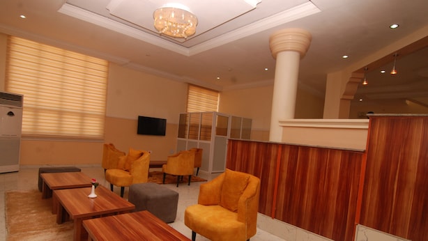 A modern lobby with wooden furniture, a chandelier, and a large column. - Fisher Suites and Apartments (Abuja)