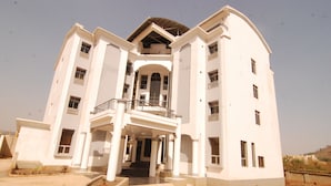 A multi-story building with a central entrance, balconies, and a flat roof. - Fisher Suites and Apartments (Abuja)