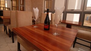 A dining table with a bottle of wine and two wine glasses. - Fisher Suites and Apartments (Abuja)