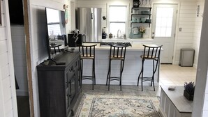 Une cuisine dotée d’un îlot central, de tabourets de bar, d’un réfrigérateur et d’un évier.